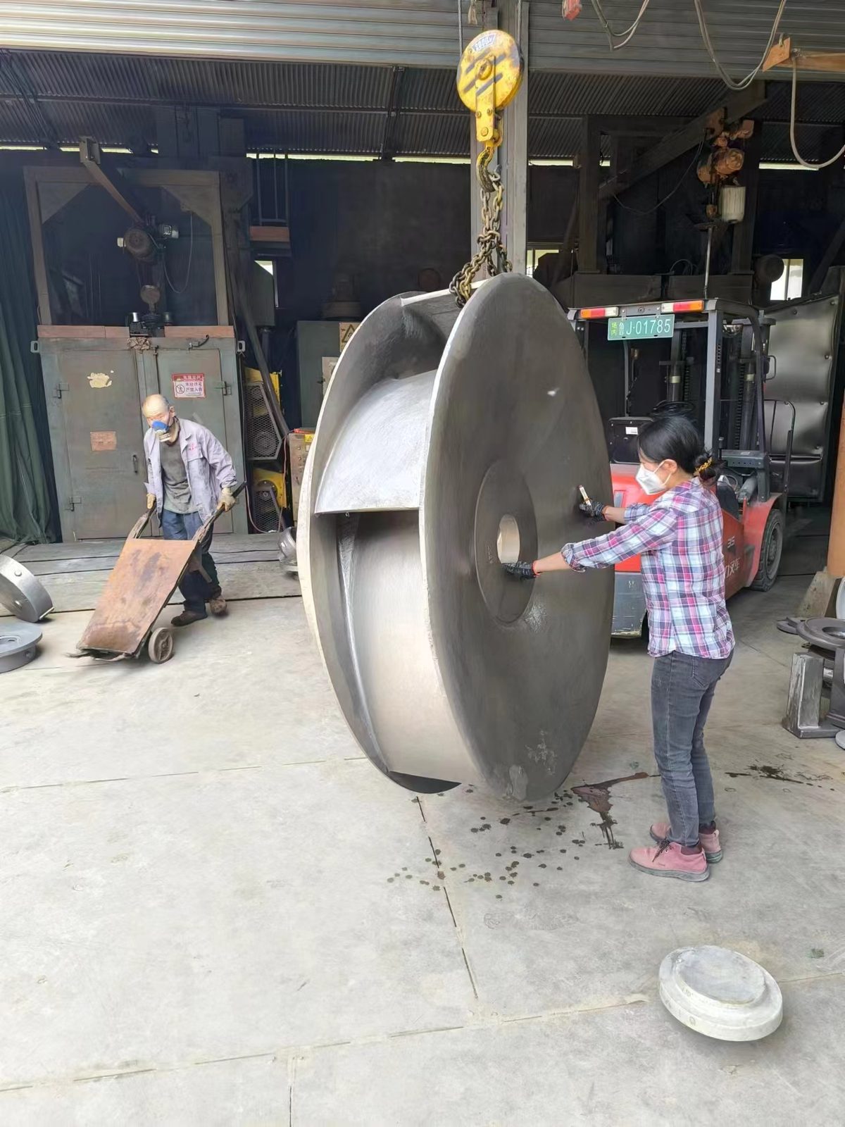 Two-tonne CD4MCu impeller slung from a crane, showing the vane passage and shroud